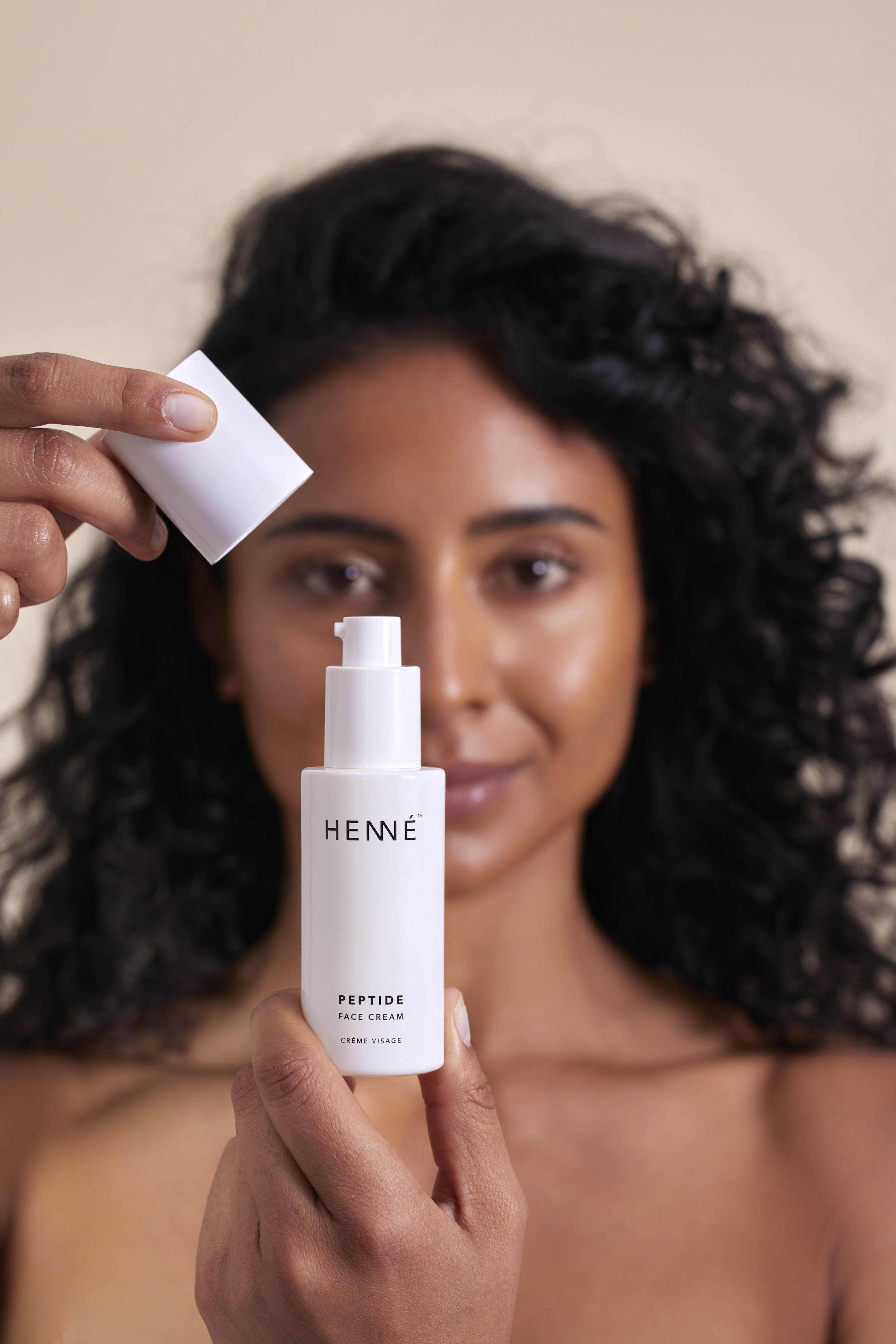 woman holding open face cream tube