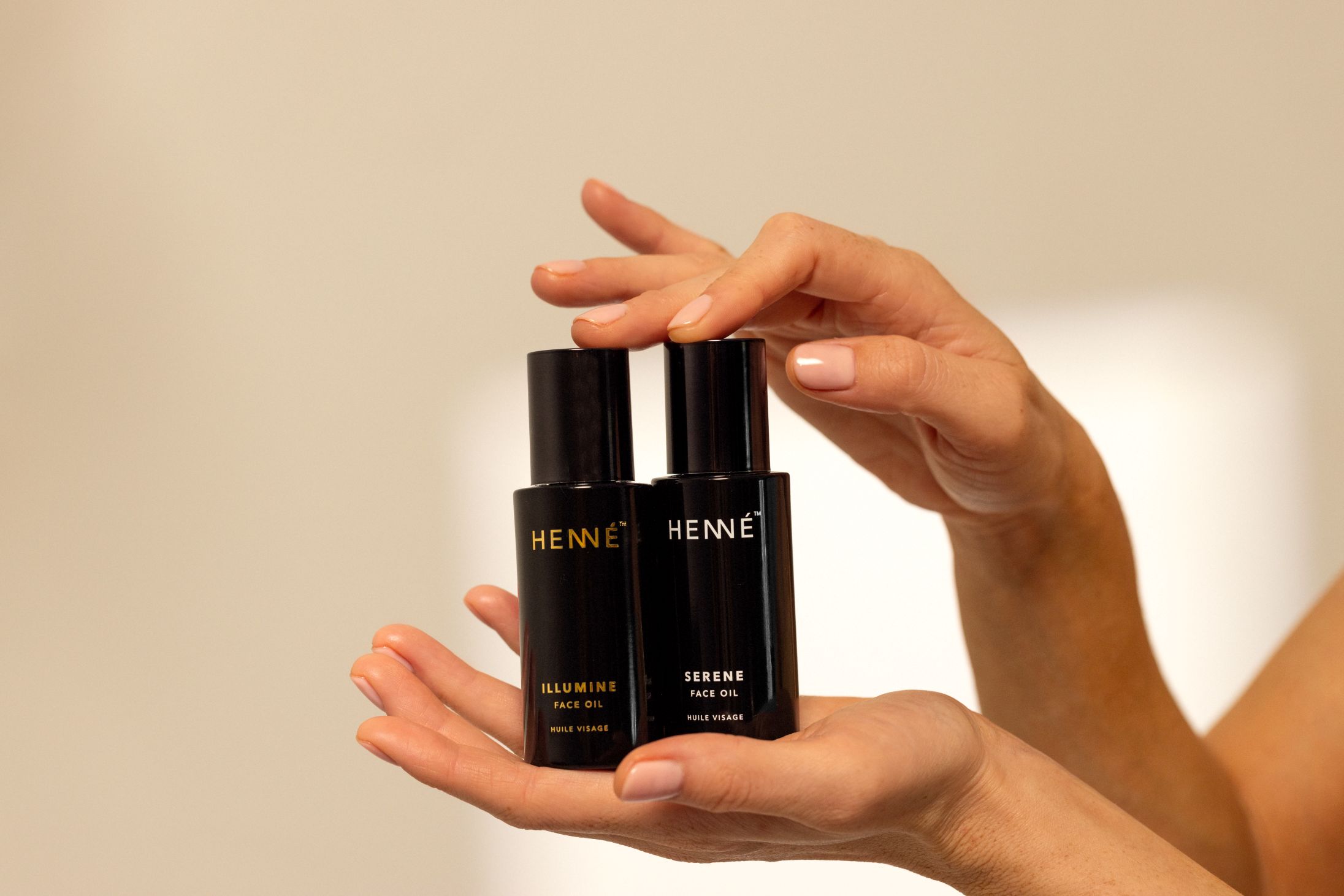 hands holding two face oil bottles